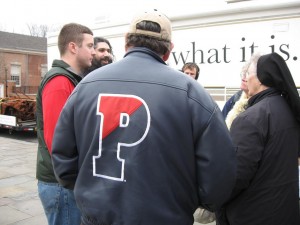 Jonathan Harvey and Esam Pasha speak to a crowd on the street, including Harvey's father Paul, wearing a Penn jacket.