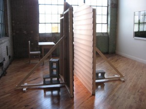 Leah Bailis, Facades, 2009, cardboard, paint, wood, cinderblocks and light, with Tables and Chairs in the background. Both pieces, dimensions variable, as installed in FLUXspace