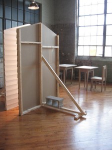 Leah Bailis, Facades, 2009, cardboard, paint, wood, cinderblocks and light, with Tables and Chairs in the background. Both pieces, dimensions variable, as installed at FLUXspace