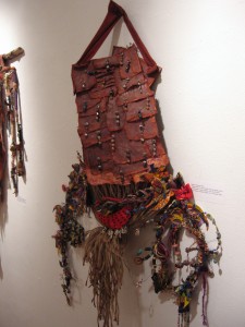 Martina Johnson-Allen, Breast Plate II, mixed media, museum board, acrylic painted papers, beads, feathers, wire, shells, fiber, twine, buttons, selected objects, 24 x 1 inches, 2009