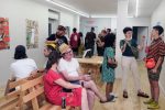 A crowd of visitors at a Commonweal Gallery exhibition opening have animated conversations about the art.