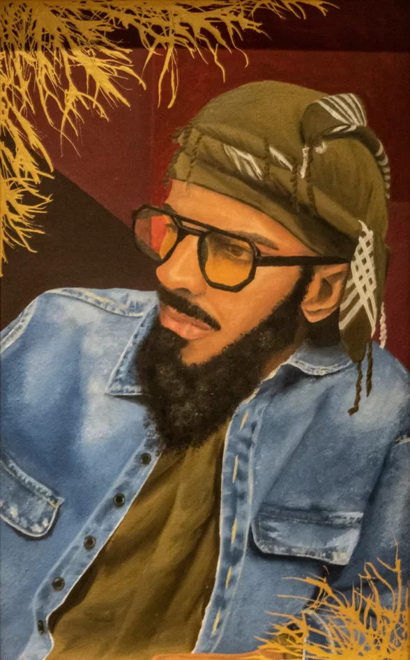 An oil painting shows the head, shoulders and chest of a young Black man with beard and mustache wearing black glasses and a fashionable head wrap and t-shirt in matching color with a jean jacket on top