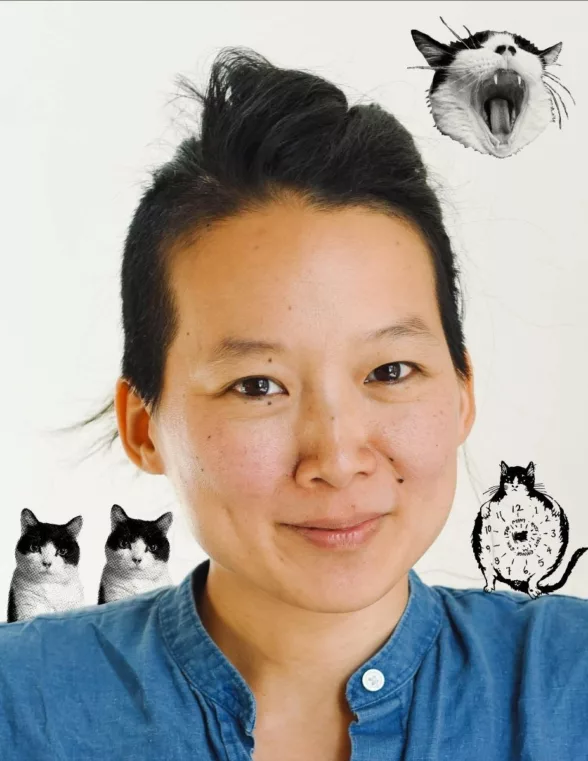 A closeup photo shows a smiling woman wearing her black hair up and a blue denim shirt surrounded by three photos of a black and white cat in the white background, at shoulder level, and another photo of a yawning black and white feline above her head.